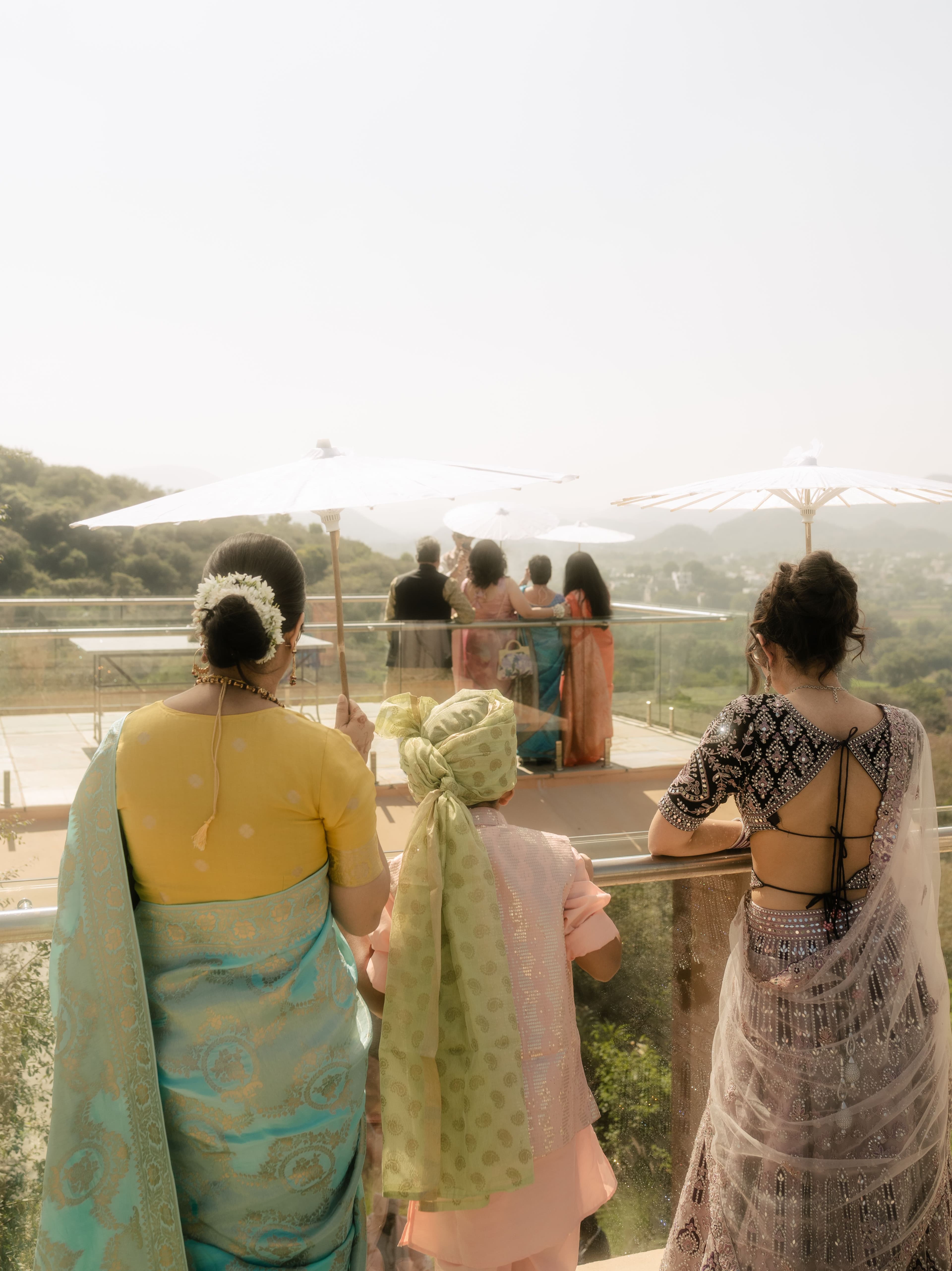 Guests under white parasols watching a distant ceremony from a terrace